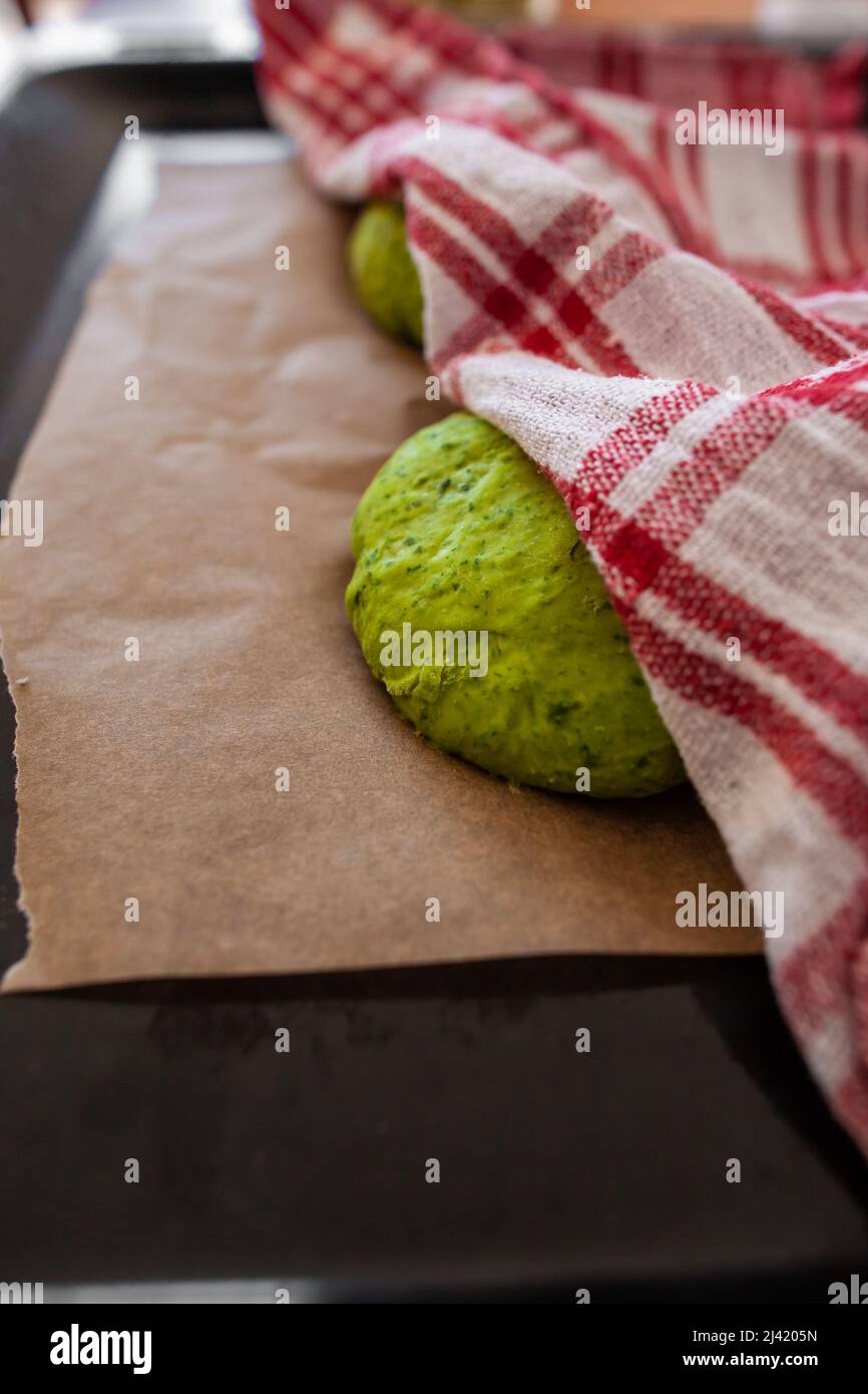https://c8.alamy.com/comp/2J4205N/green-dough-rising-under-checkered-kitchen-towel-on-brown-baking-paper-on-black-baking-tray-closeup-yeast-dough-covered-with-red-white-kitchen-cloth-2J4205N.jpg
