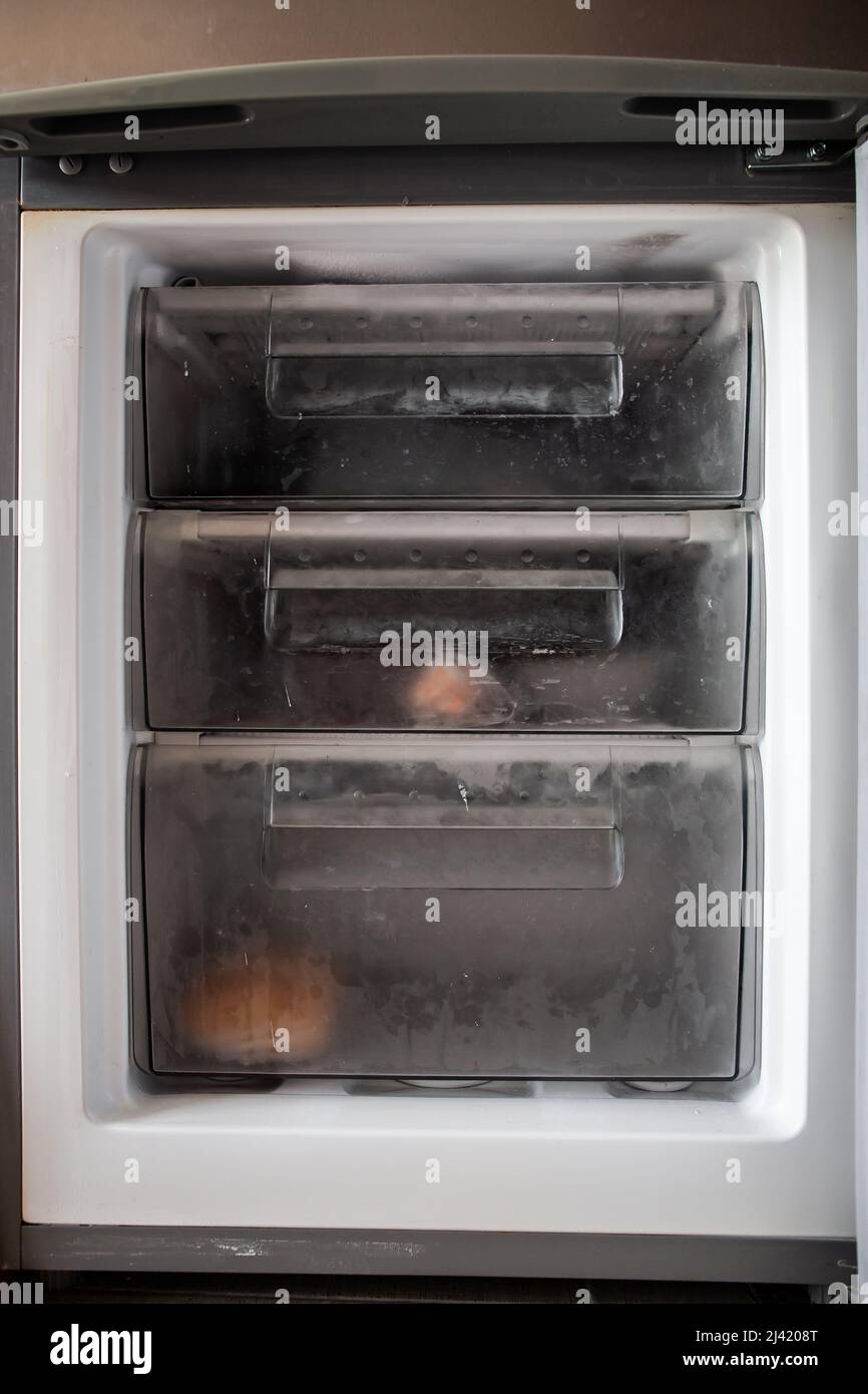 Opened freezer with transparent drawers with some packaged frozen food