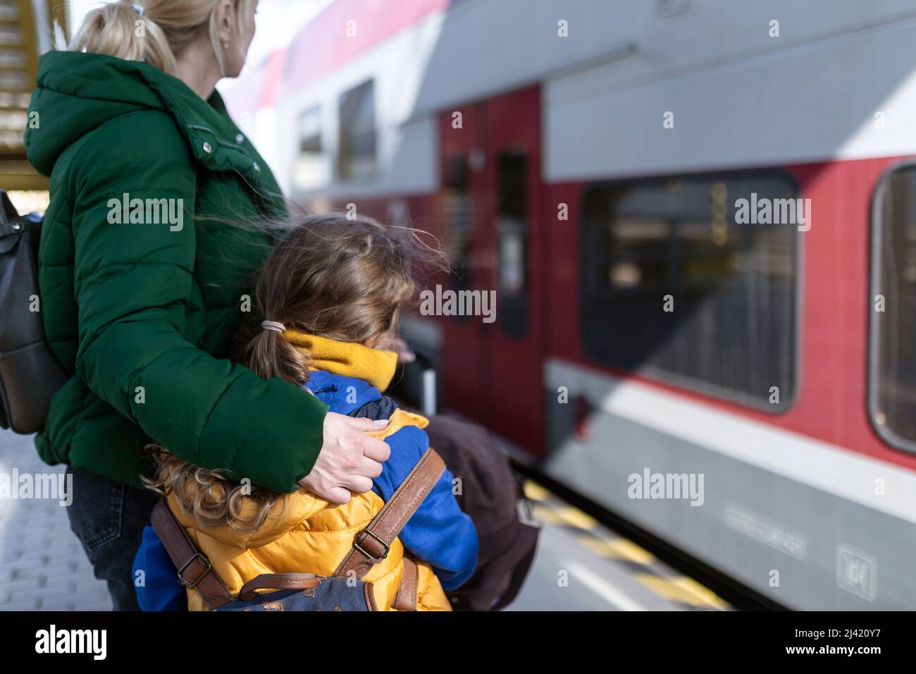 Ukrainian woman with daughter saying good bye and waving to his family in train leaving Ukraine due to Russian invasion in Ukraine. Stock Photo