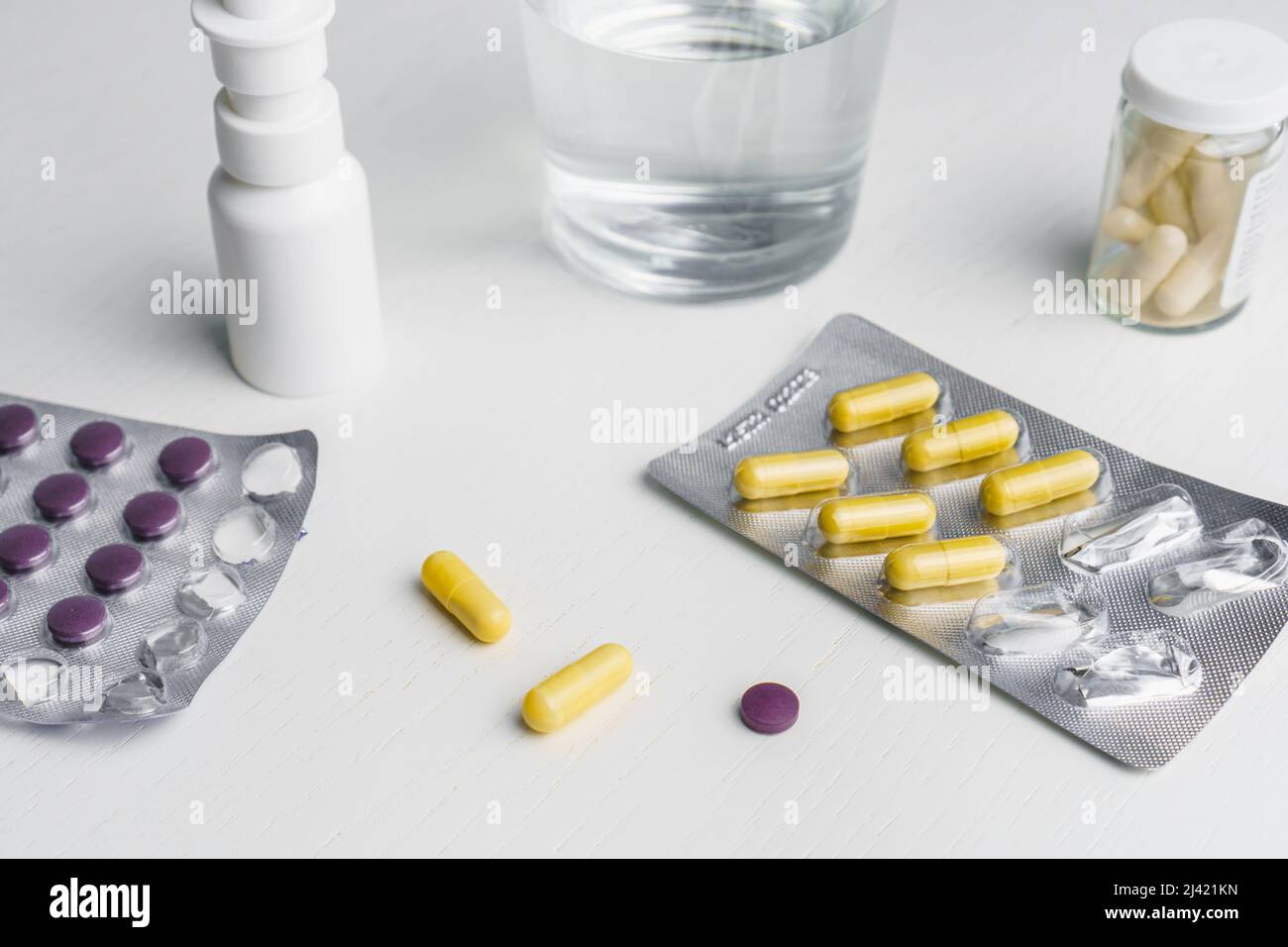 Glass of water, spray for nose, pills in blister and used napkins on table. Flu treatment concept Stock Photo