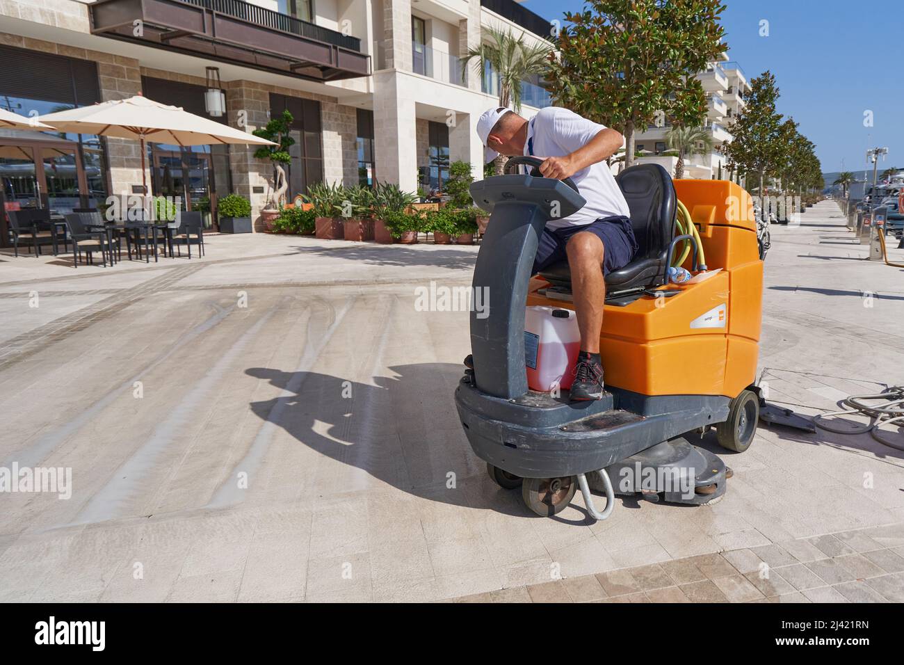 TIVAT, MONTENEGRO - JULY 15, 2021: A worker washes sidewalks on a special cleaning machine Taski Stock Photo
