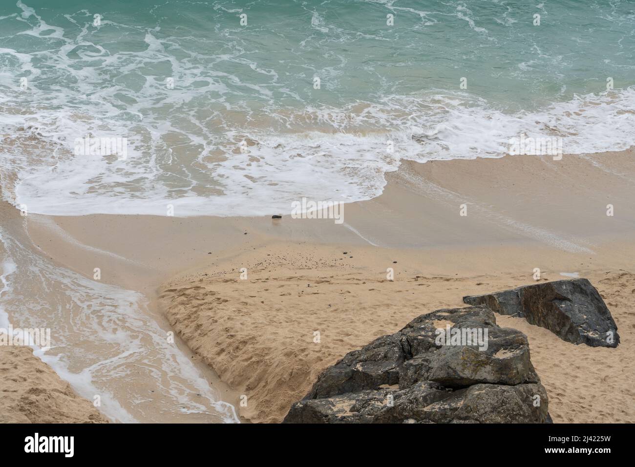 White waves hitting the yellow sand at the beach at St Ives, Cornwall, UK Stock Photo