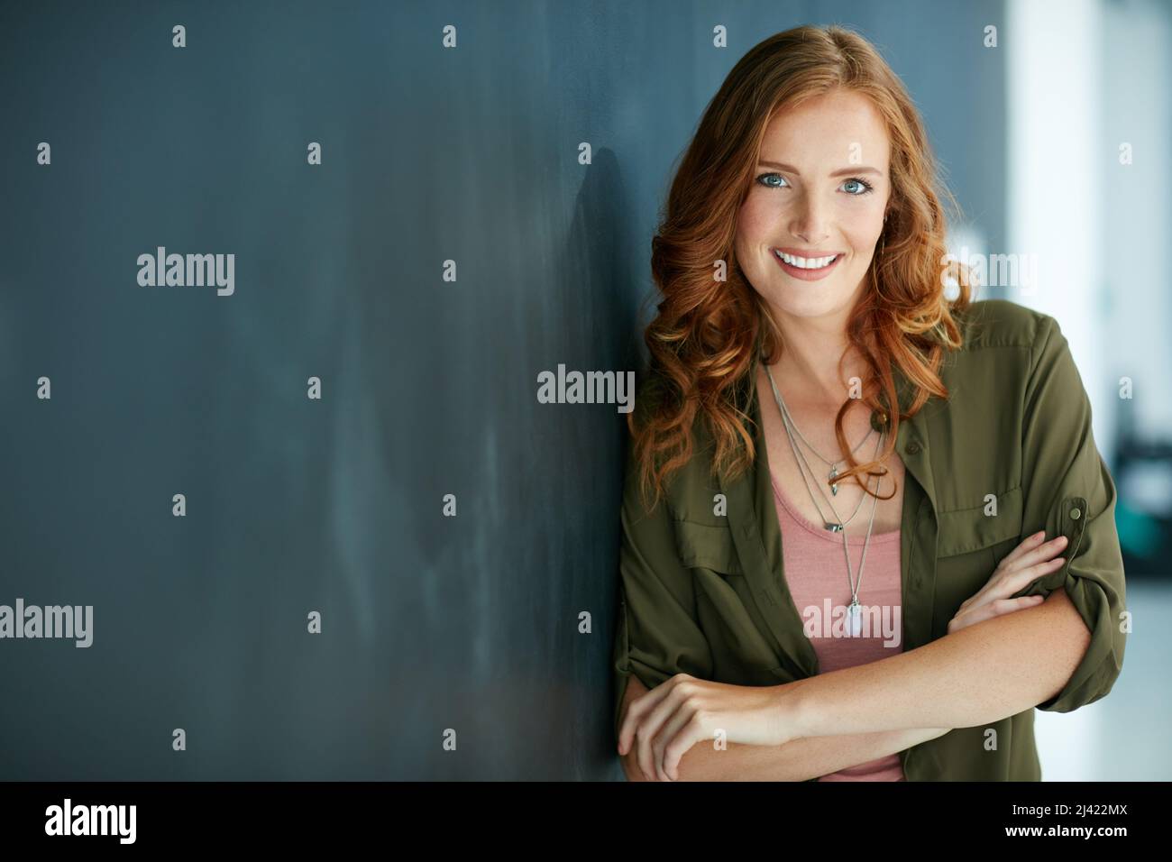 Confidence is my favourite accessory. Portrait of a confident young woman leaning against a blackboard. Stock Photo