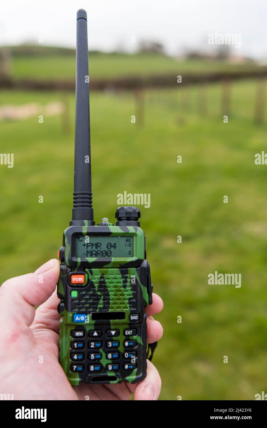 Man holds a two-way radio with camouflage pattern. Stock Photo