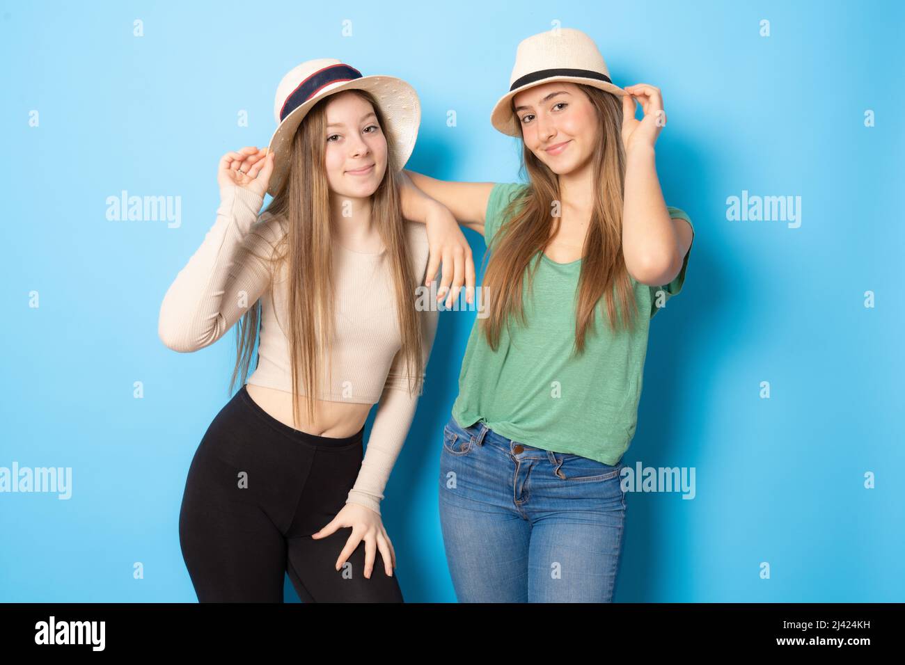 Portrait of two cheerful young women wearing straw hat standing ...