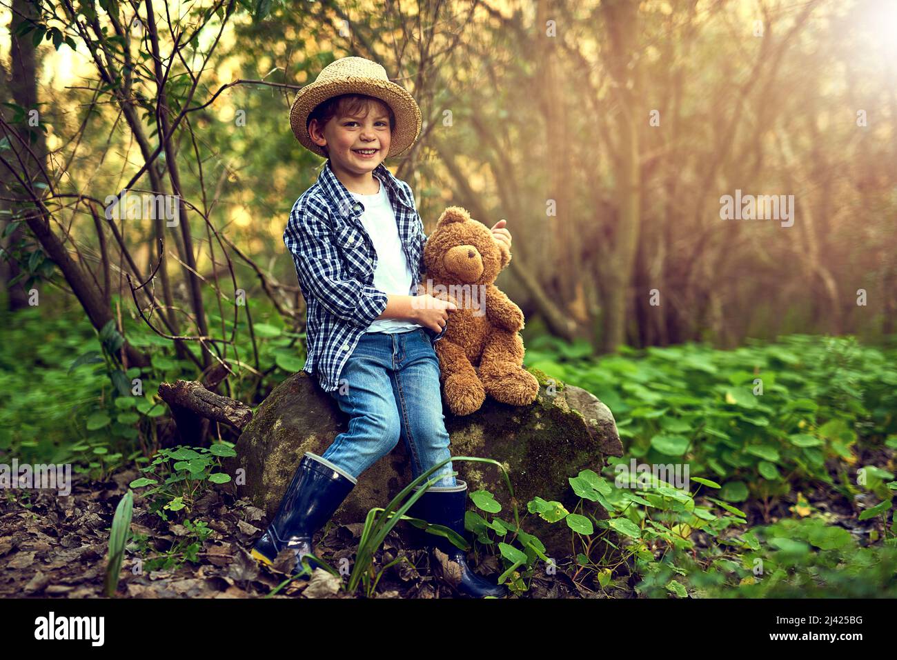 Theres no better companion in the woods. Shot of a little boy sitting in the forest with his teddy bear. Stock Photo