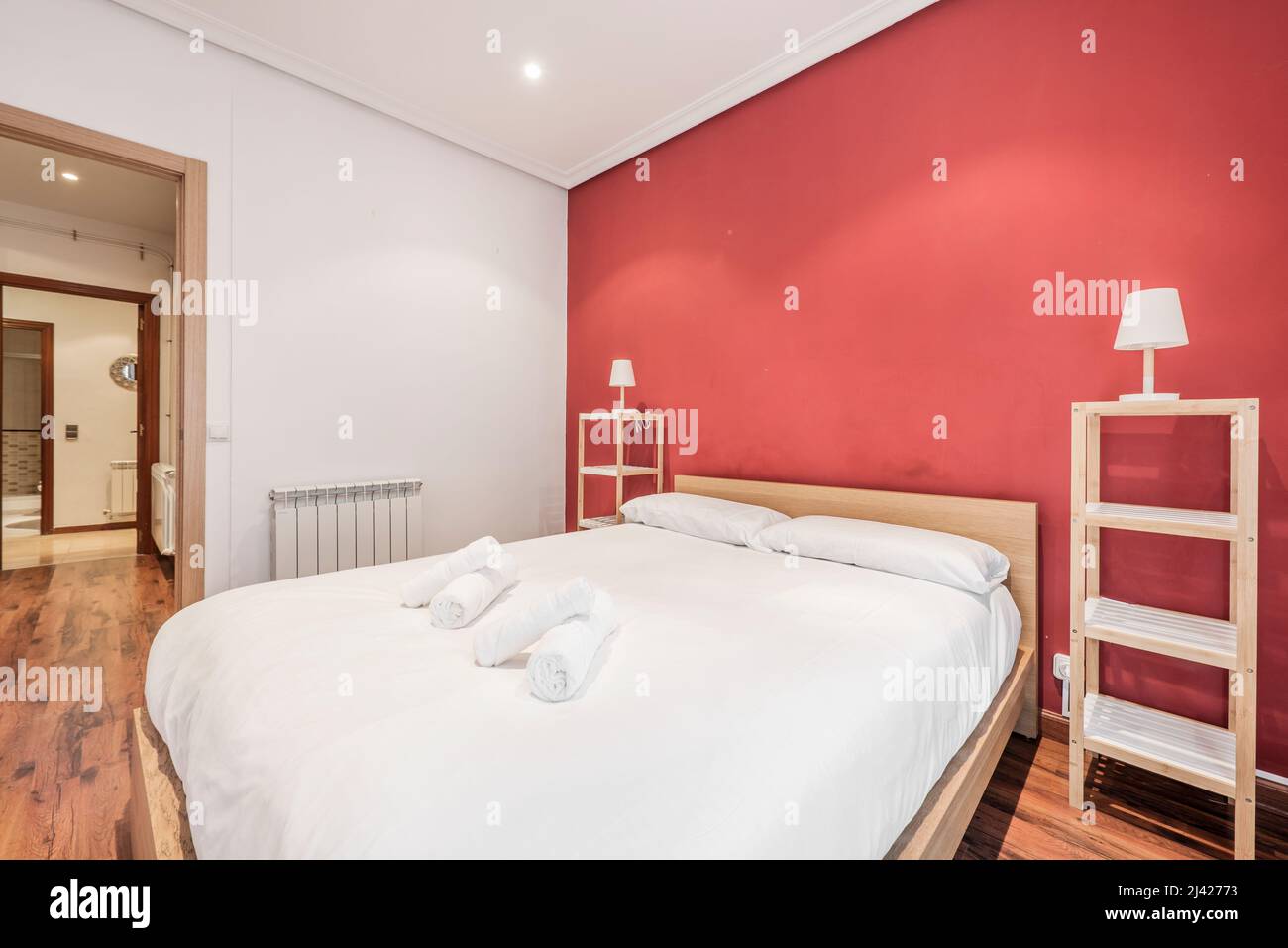 Bedroom with king size bed with wooden headboard, twin wooden shelves