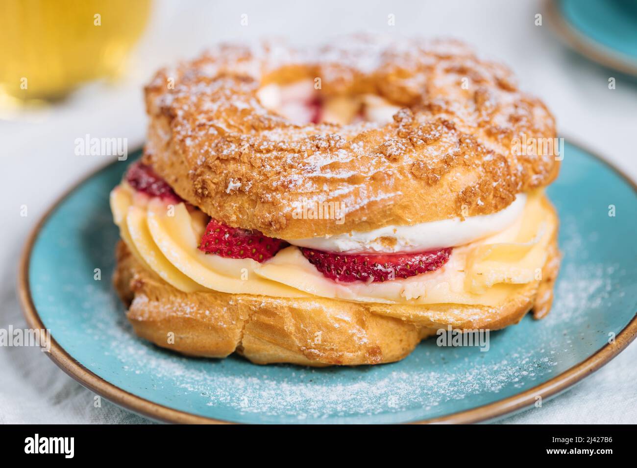 Traditional French Dessert called Paris Brest on a light grey background with powder sugar and