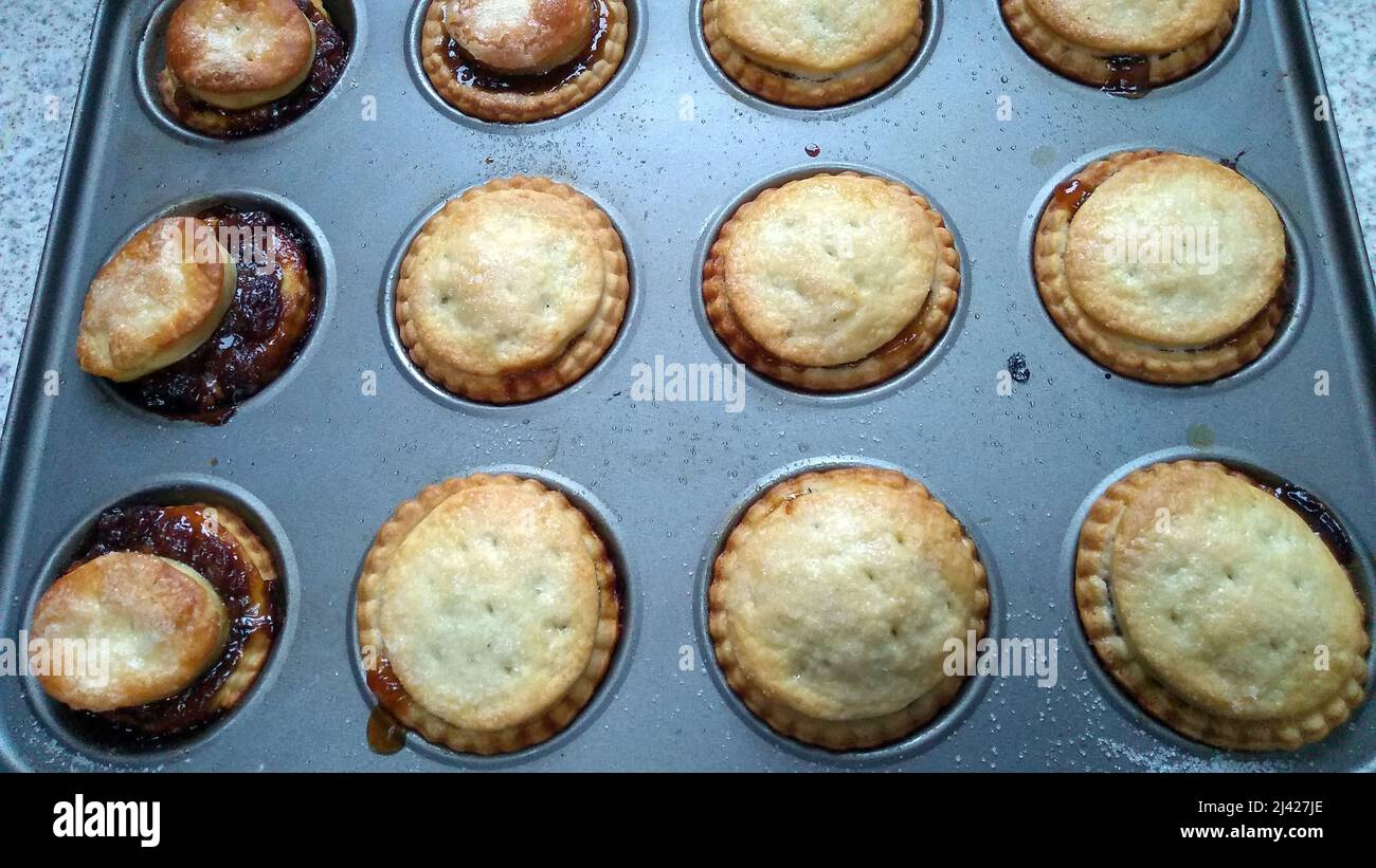 HAYDOCK. MERSEYSIDE. ENGLAND. 12-07-21. A tray of home made mince pies fresh from the oven with the filling bursting from some of them. Stock Photo