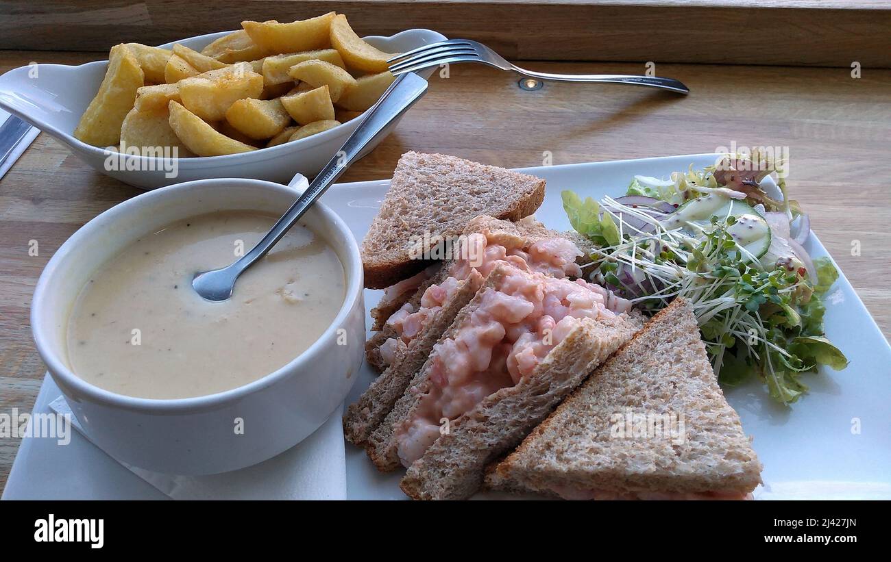 LYTHAM. LANCASHIRE. ENGLAND. 11-14-21. A meal of mushroom soup, prawns on wholemeal bread and a side order of chips. they are lit by natural light fro Stock Photo