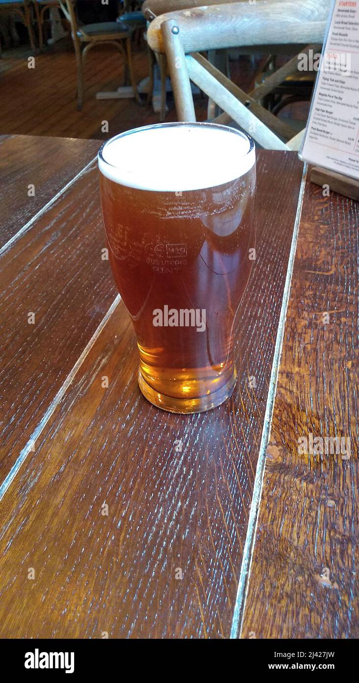 WINDERMERE. CUMBRIA. ENGLAND. 03-26-22. A pint of beer on a table top in a Lake District pub. Stock Photo