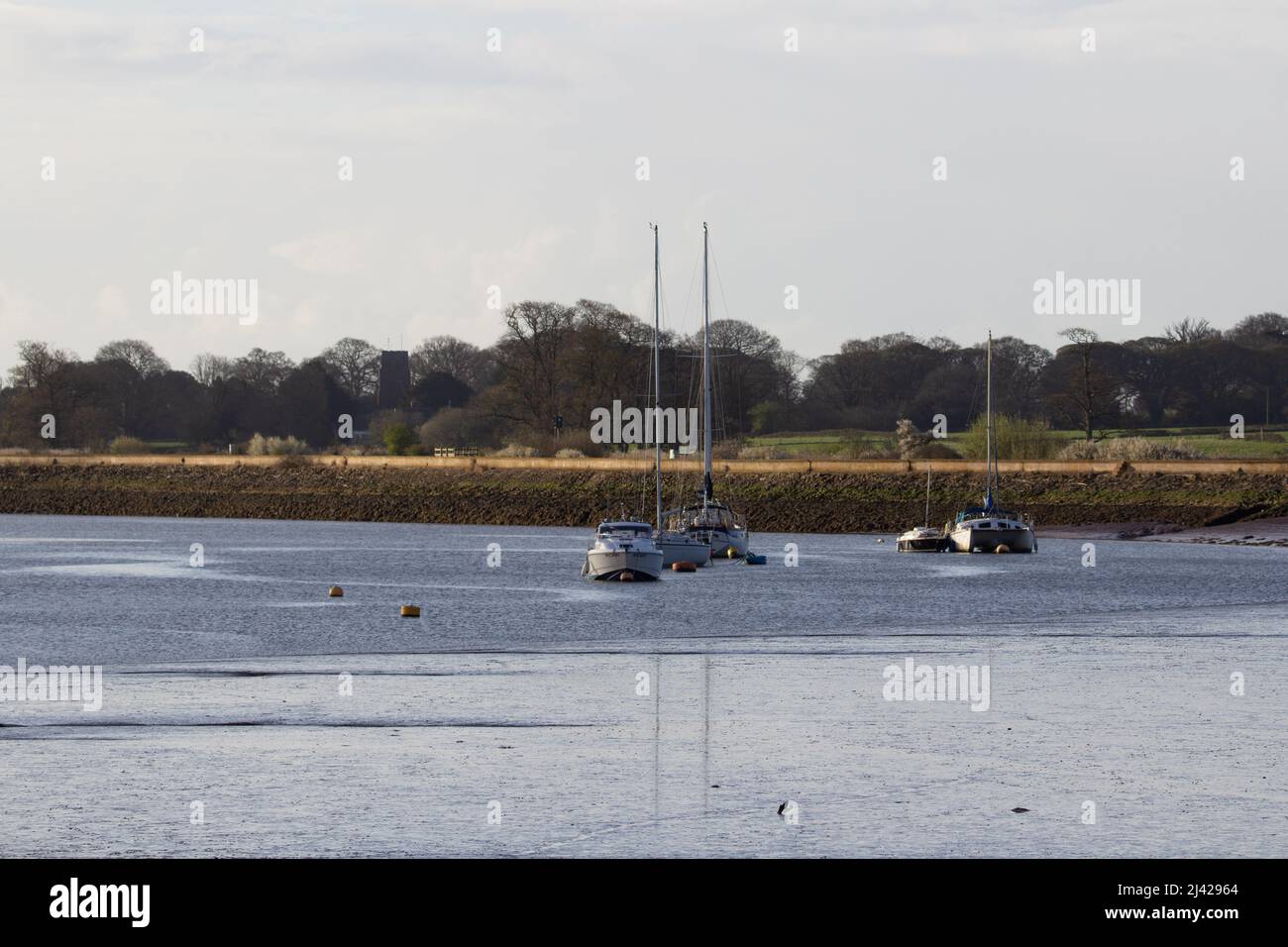 EXETER, UK - APRIL 6, 2021 sailboats moored in the Exe estuary with flood defence in the background Stock Photo