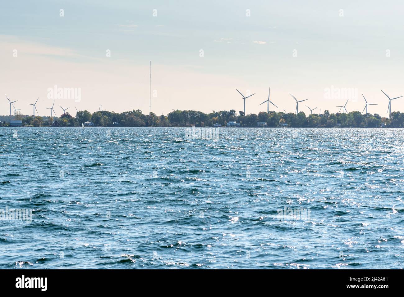 Wind farm on a Island with forested shores in a lake on a sunny autumn day Stock Photo