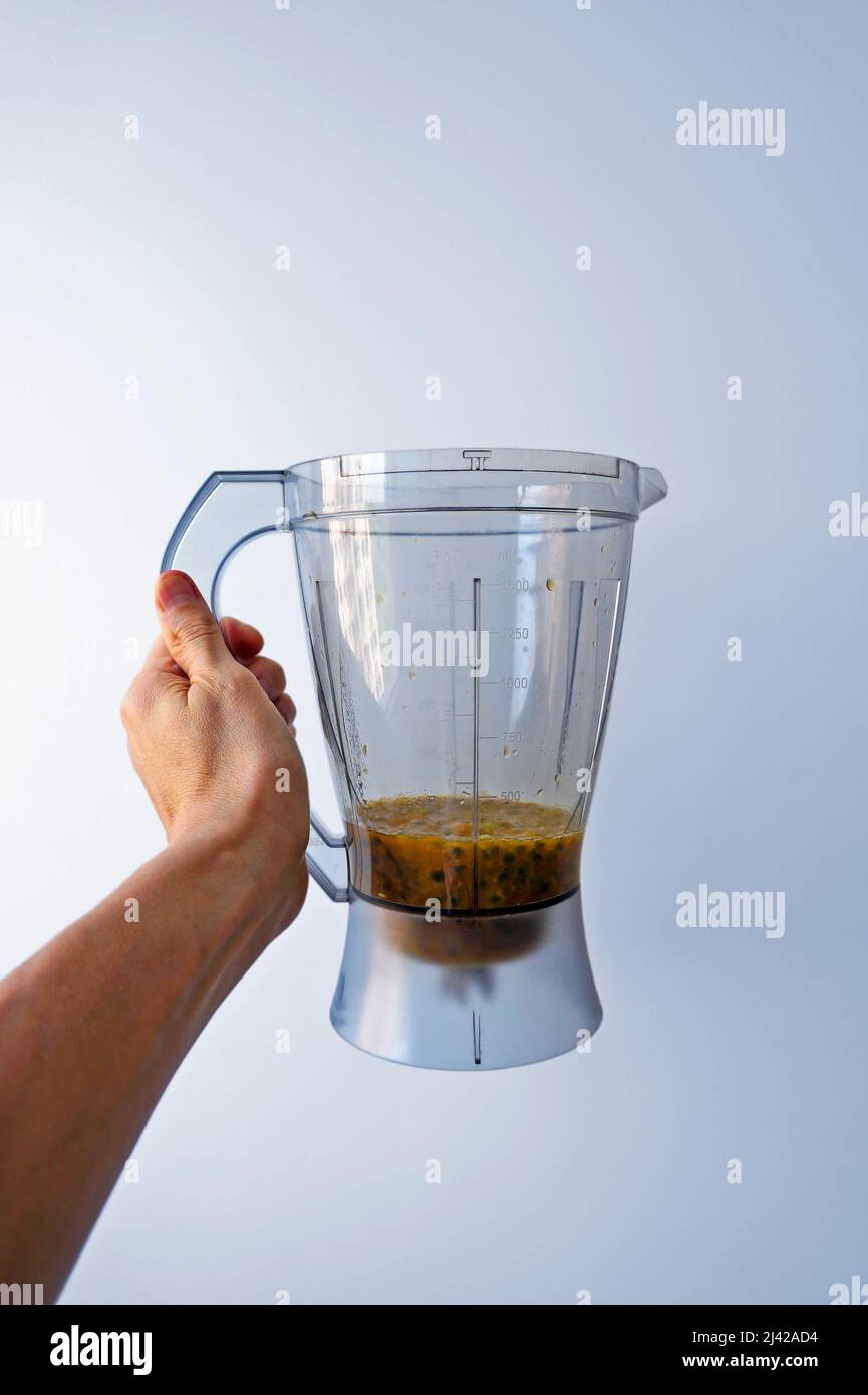 Blender cup with passion fruit pulp on hand Stock Photo
