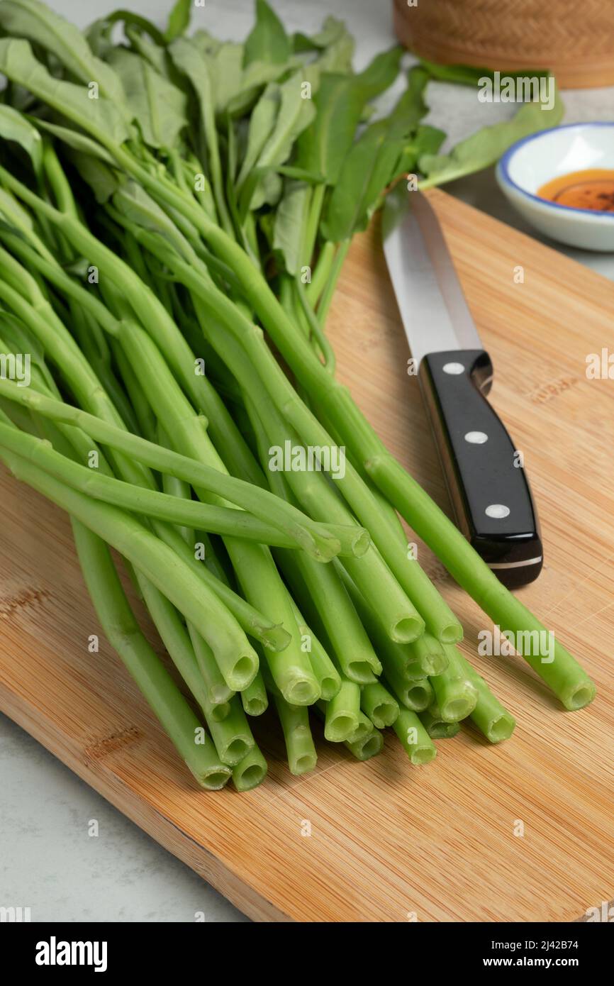 Fresh raw green water spinach,  kangkong, on a wooden cutting board close up Stock Photo