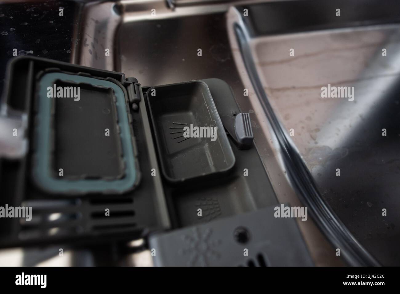 Closeup of opened dishwasher dispenser on dirty opened door with streaks and stains Opened