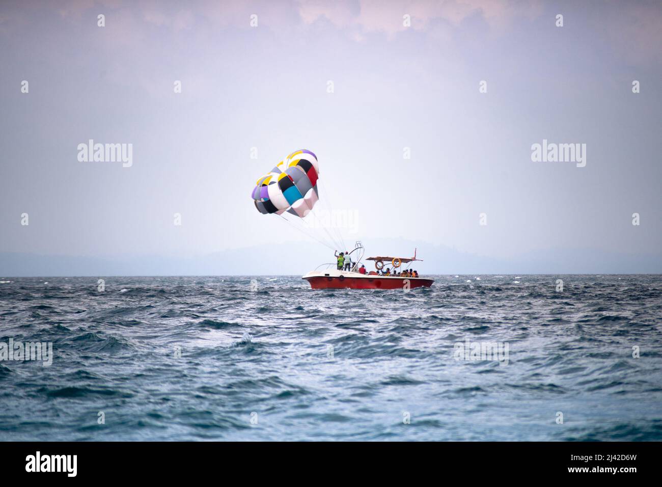 para gliding sailing behind power speed boat floating against cloudy sky at beach in havelock andaman nicobar island India showing adventure sports Stock Photo