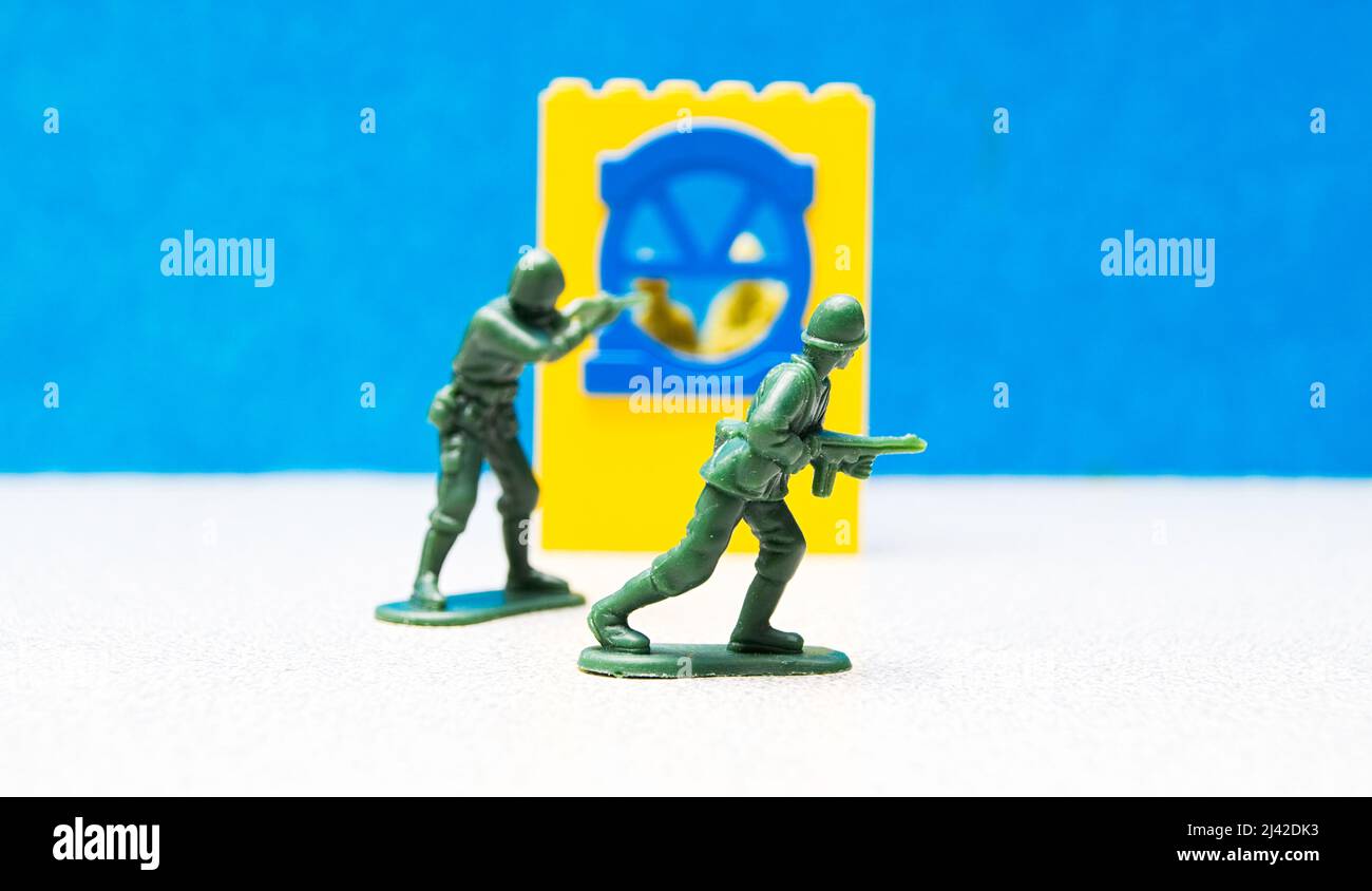 Plastic Toy Soldiers in the heat of battle, with a window in the backdrop and plastic soldiers inside Stock Photo