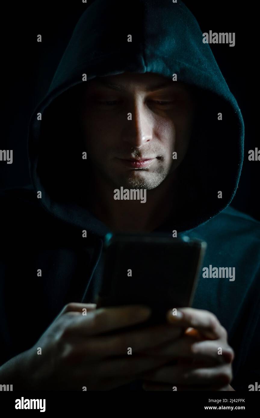 Portrait of a young hooded man who is using a smartphone Stock Photo