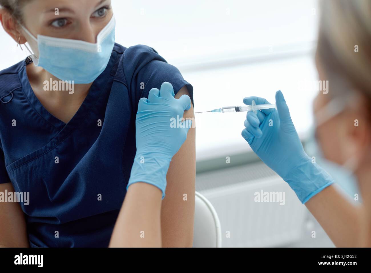 wonan doctor or nurse giving shot or vaccine to patient shoulder. Vaccination and prevention against flu or virus pandemic. Covid-19 or coronavirus va Stock Photo