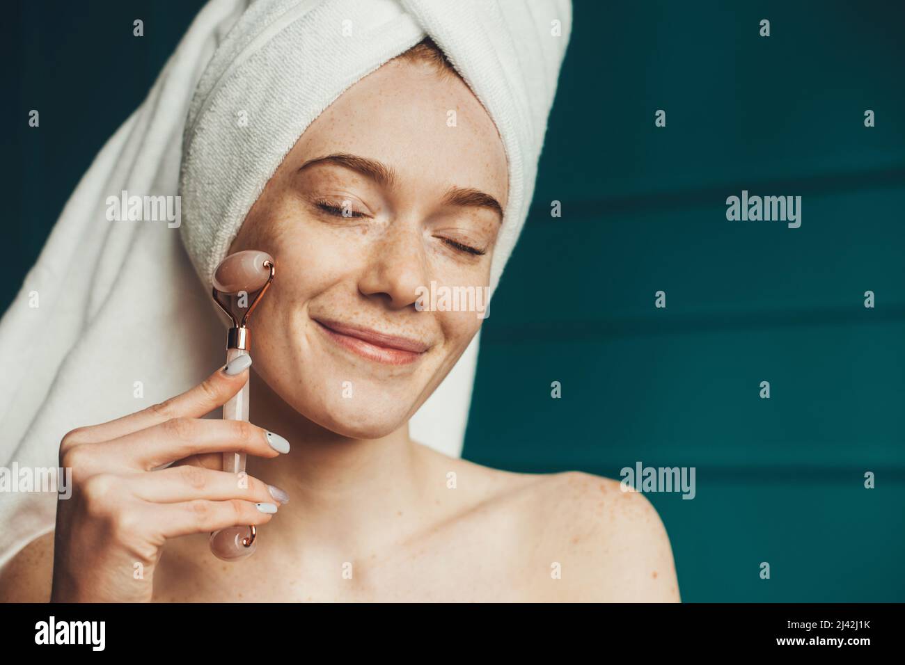 Portrait of a freckled woman after shower smiling while using jade