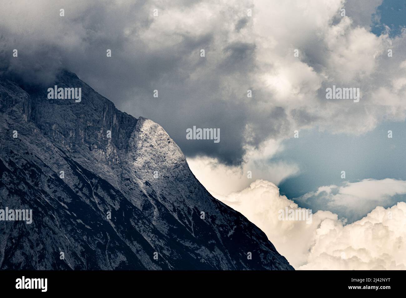 Thunderclouds starting to cover a mountain flank at a sudden weather change in the Tyrolean Alps Stock Photo