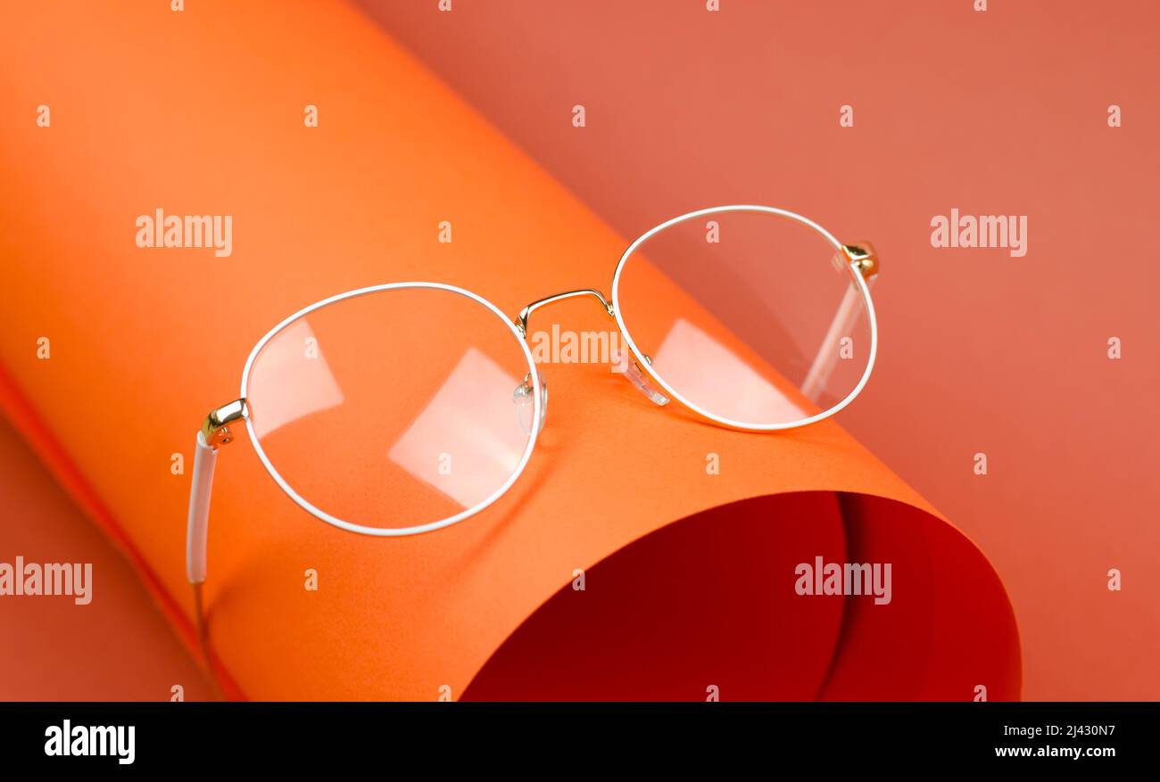 Glasses with round lenses in a white frame on an orange background