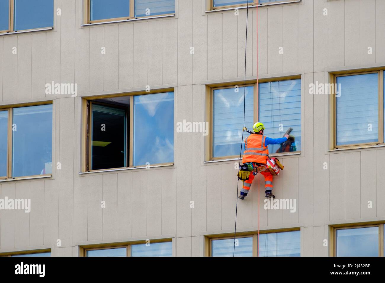 Minsk, Belarus - April 11, 2022: Industrial climber washes windows on the facade of a building in the business district Stock Photo