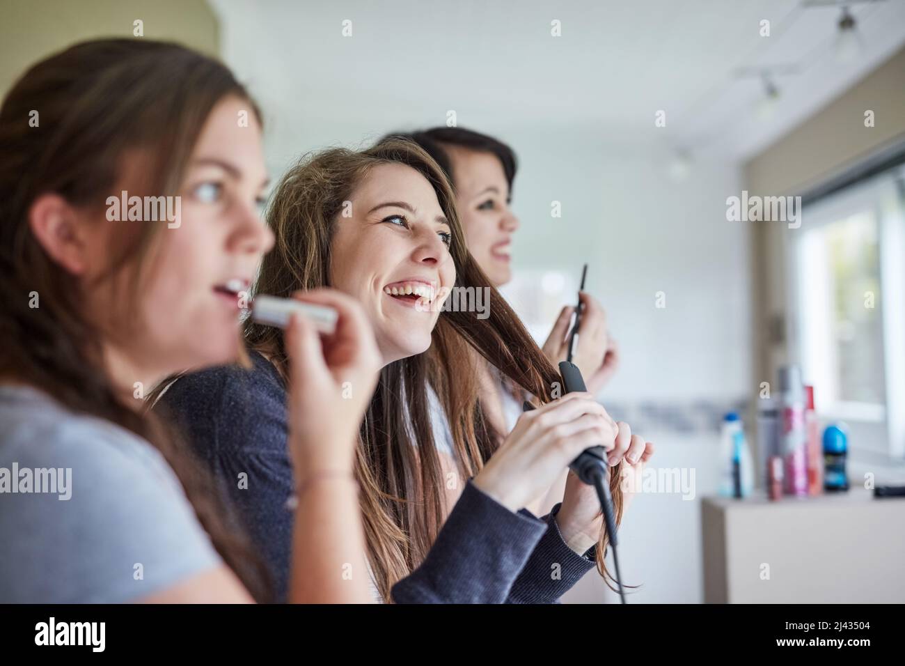 Feeling pretty. Cropped shot of three young friends putting on makeup and styling their hair in the bathroom. Stock Photo