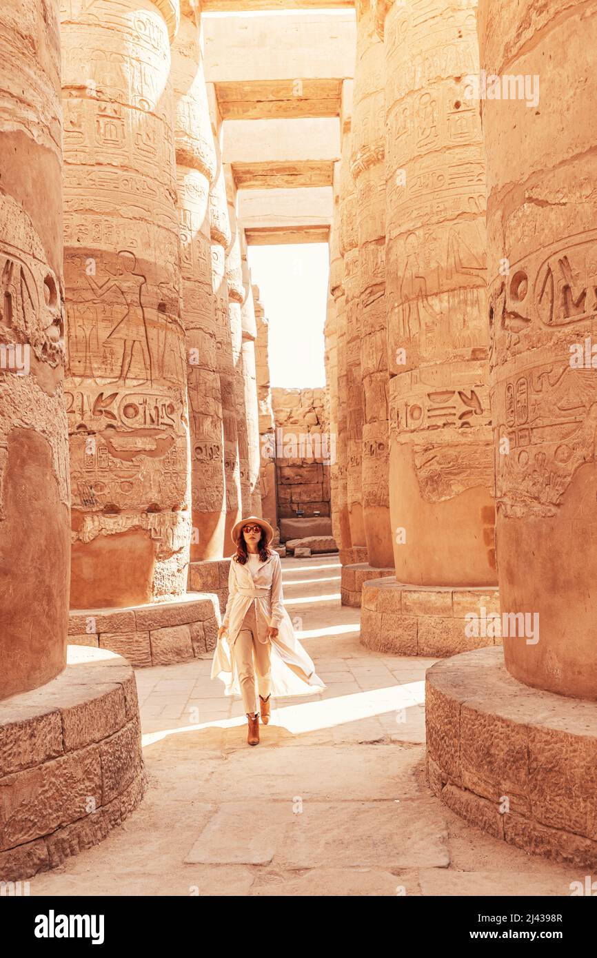 Happy woman traveler explores the ruins of the ancient Karnak temple in the  heritage city of Luxor in Egypt. Giant row of columns with carved hierogly  Stock Photo - Alamy