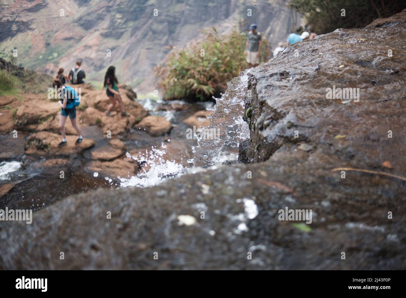 Kids playing below a splashing waterfall Stock Photo
