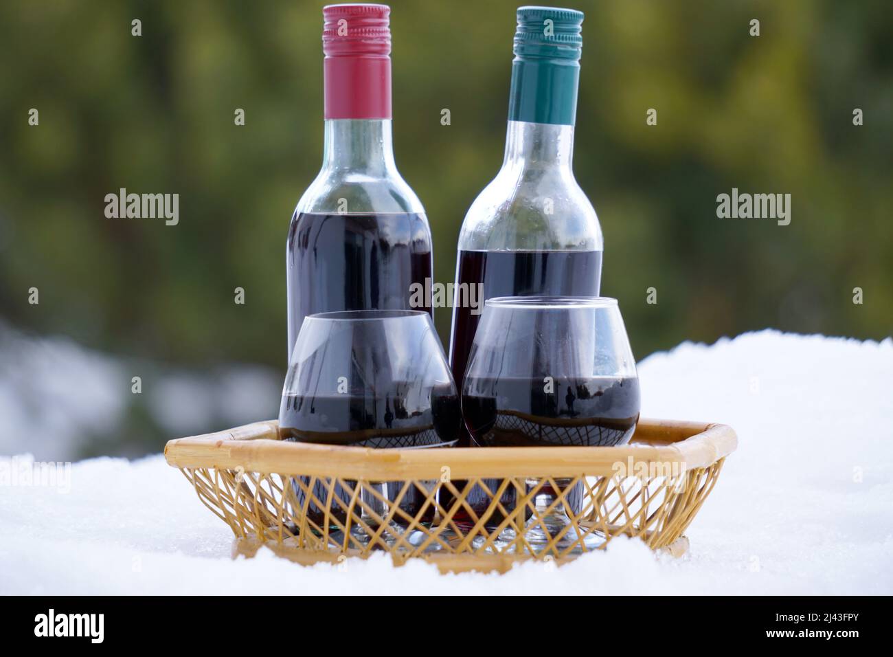 mini bottles of red wine in a basket on cold snow in the middle of winter Stock Photo