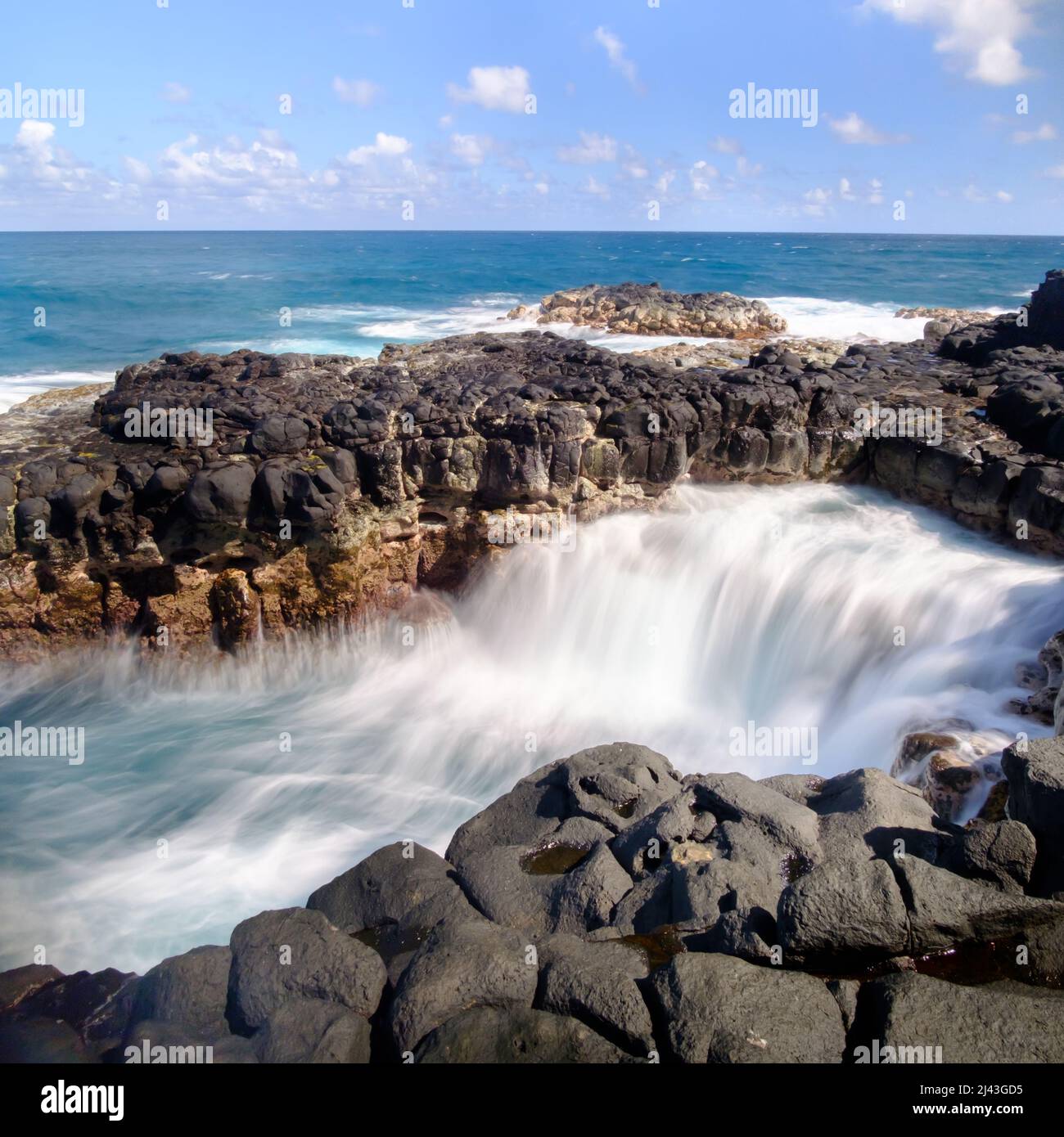 Long exposure of ocean waves draining from a lava rock shelf Stock Photo