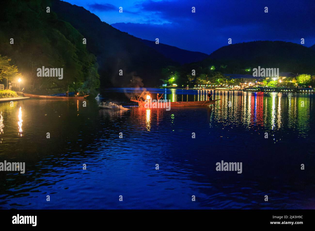 Small boat with fire used to lure fish on blue river in Kyoto at night Stock Photo
