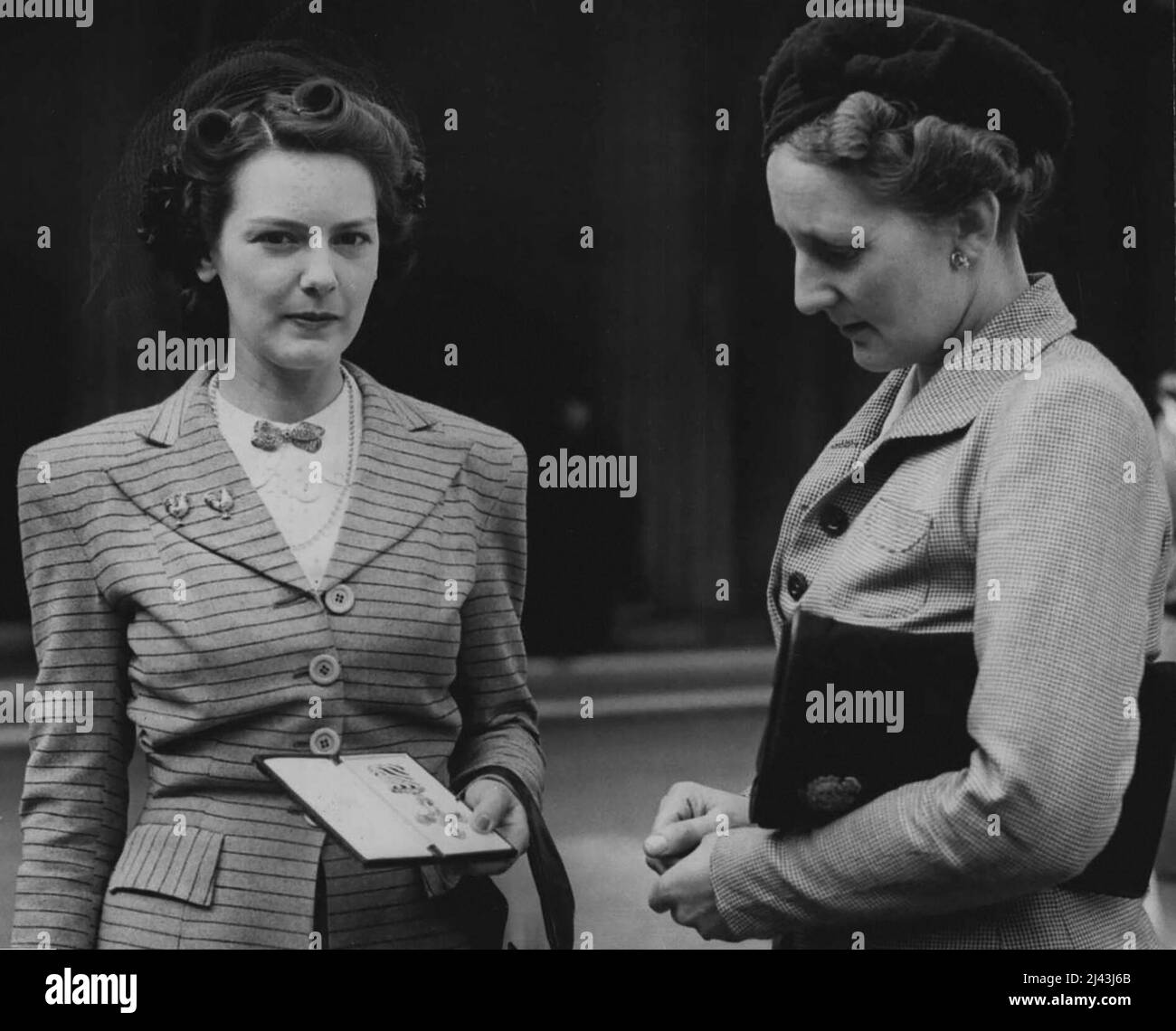 At a recent Investiture held by the King -- Mrs. Collyns (left) with the DFC awarded to her late husband, F/LT. Basil Collyns, of the Royal New Zealand Air Force, after receiving the decoration form the King. On right decoration from the King. On right is her mother in-law, Mrs. Uollyns. March 26, 1945. Stock Photo
