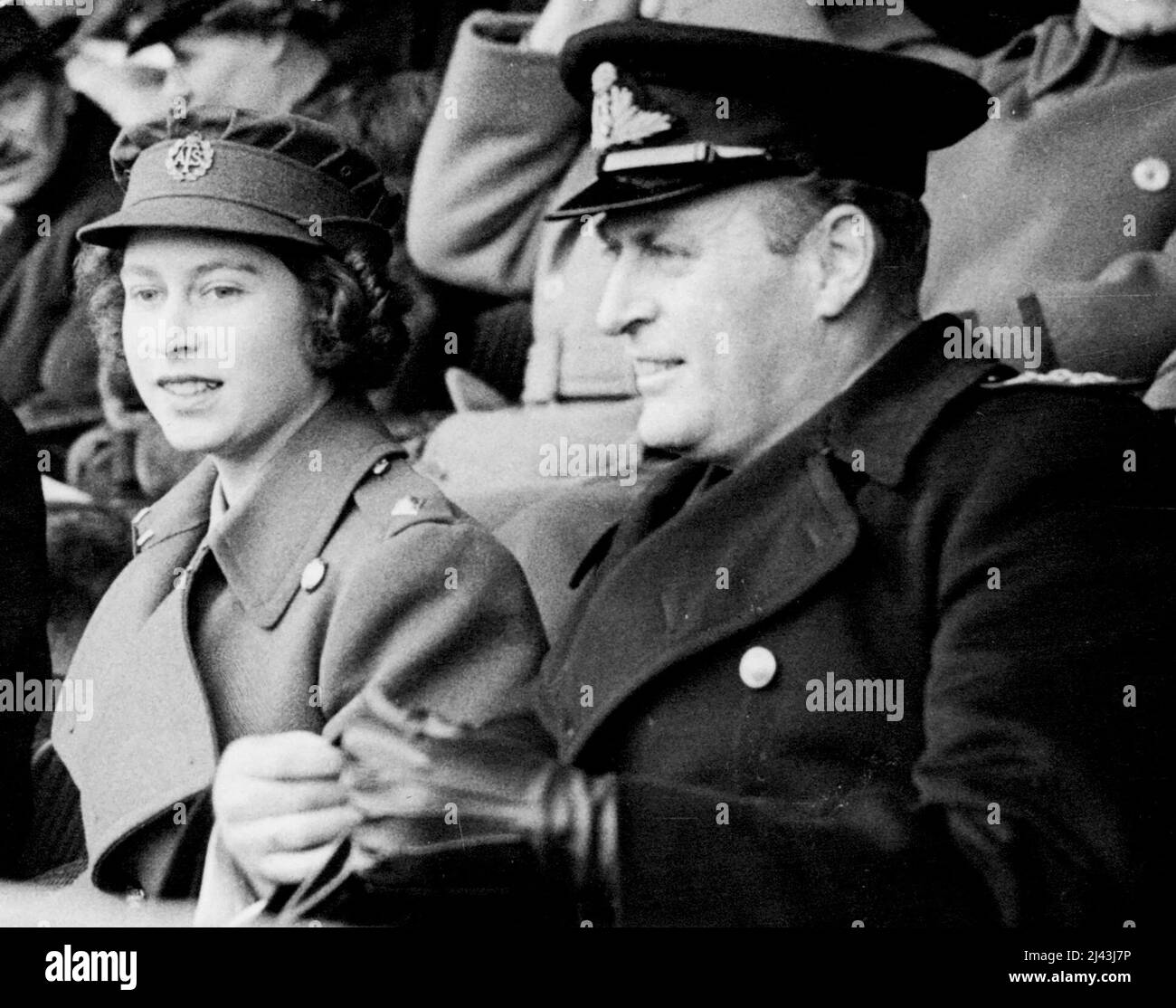 The King and Queen And Second Subaltern Elizabeth Windsor of The Watch Cup Final. Second Subaltern Elizabeth Windsor of the A.T.S. (H.R.H. Princess Elizabeth) and Prince Olaf of Norway watching the match. Princess Elizabeth looks like setting a new hair style for the women's forces - her hair was arranged in a couple role of curls - the back. Several ATS officers in the crowd remarked on the attractiveness of the Princess's hair-do. April 8, 1945. Stock Photo