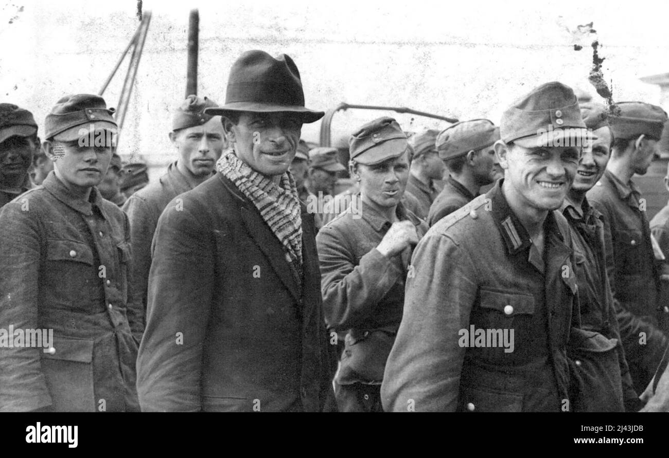 German Prisoners Arrive in Britain. They have just left the landing craft which brought them over. Prisoner in centre is still wearing 'civvies'. The boy on the left is yet in his 'teens. Officer on right looks on cheerfully. Streaming into Britain today, in overwhelming numbers, come these men of Hitler's vanquished 'Wehrmacht'. Captured in batches by the victorious Allied Armies of the West, they are illustrated here, arriving at a Southern Port. Some happy to be out of it. Some arrogant, others dejected. Some, who thought they could escape their captors, changed into civilian clothes, and Stock Photo