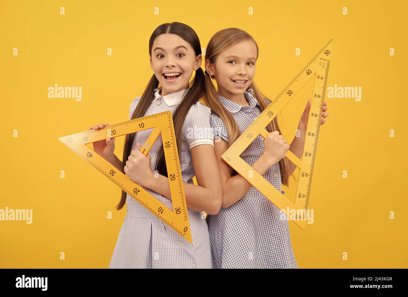Education for all children. Happy teen girls hold triangular rulers. School education. Geometry lesson Stock Photo