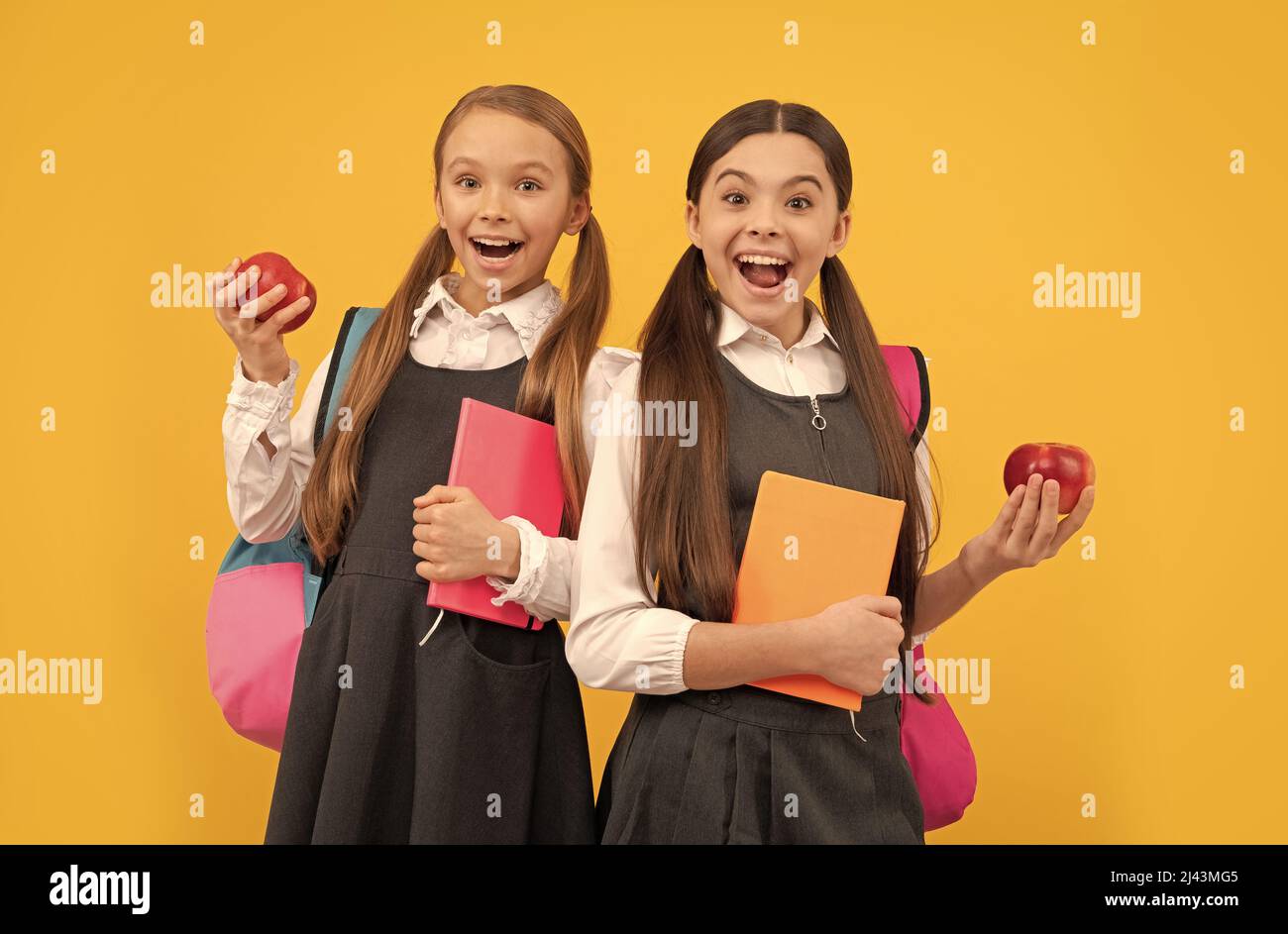 Happy kids in school uniforms hold books and apples for healthy eating school meal, snack Stock Photo