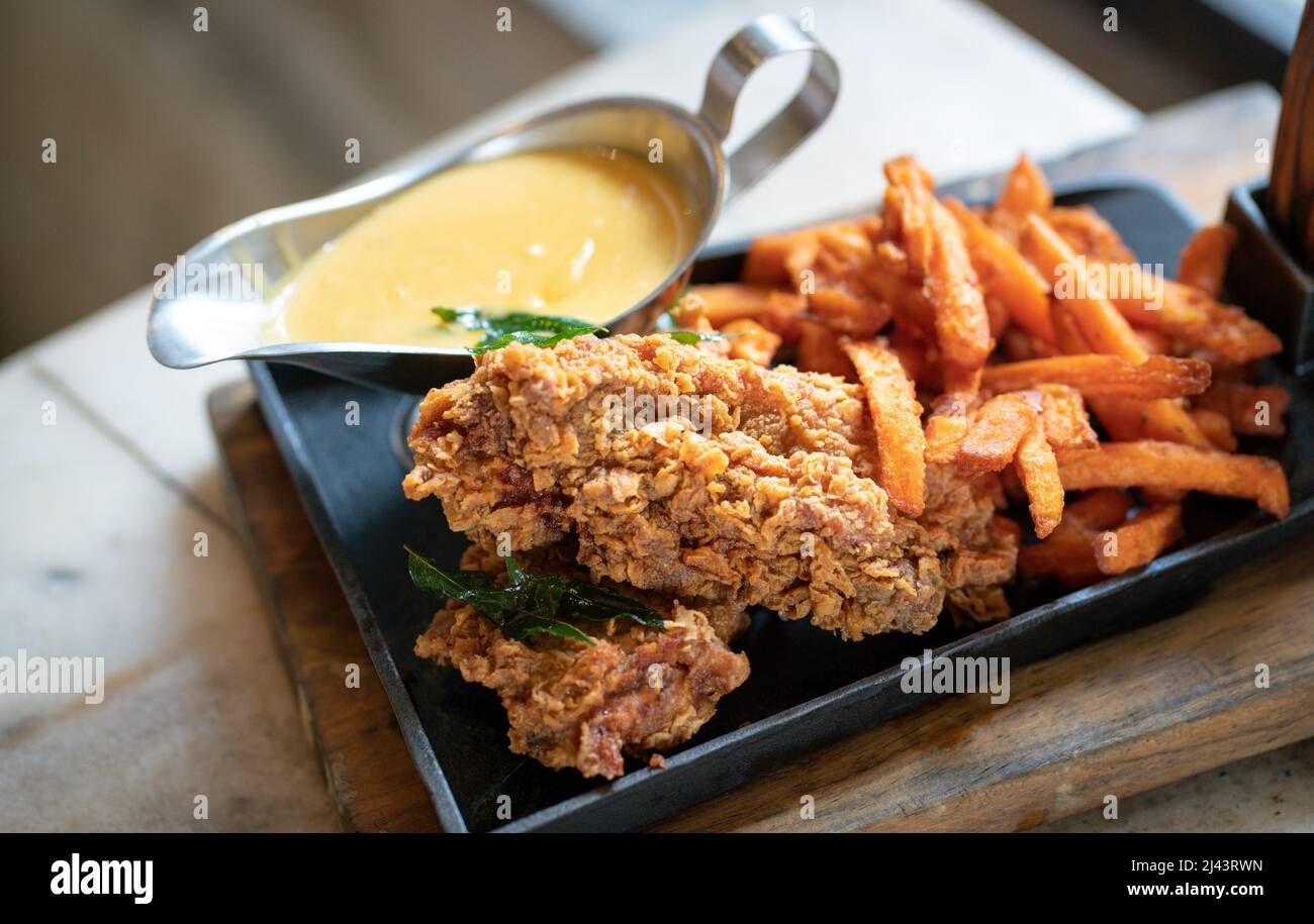 Chicken chop with chips and salted egg sauce on a grill pan Stock Photo