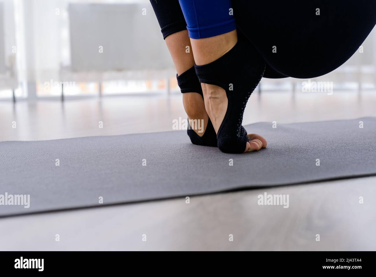 Close up Woman in purple leggings putting on her grey socks. Lady prepare for yoga workout. Concept of yoga accessories  Stock Photo