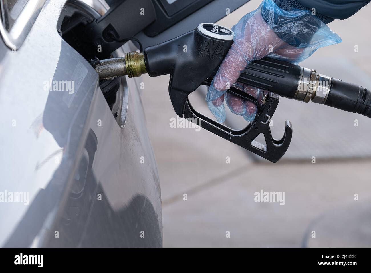 Diesel. Refueling the car.Refueling pistol in the hands of a man in a glove.A man fills up a car tank with diesel fuel. Stock Photo