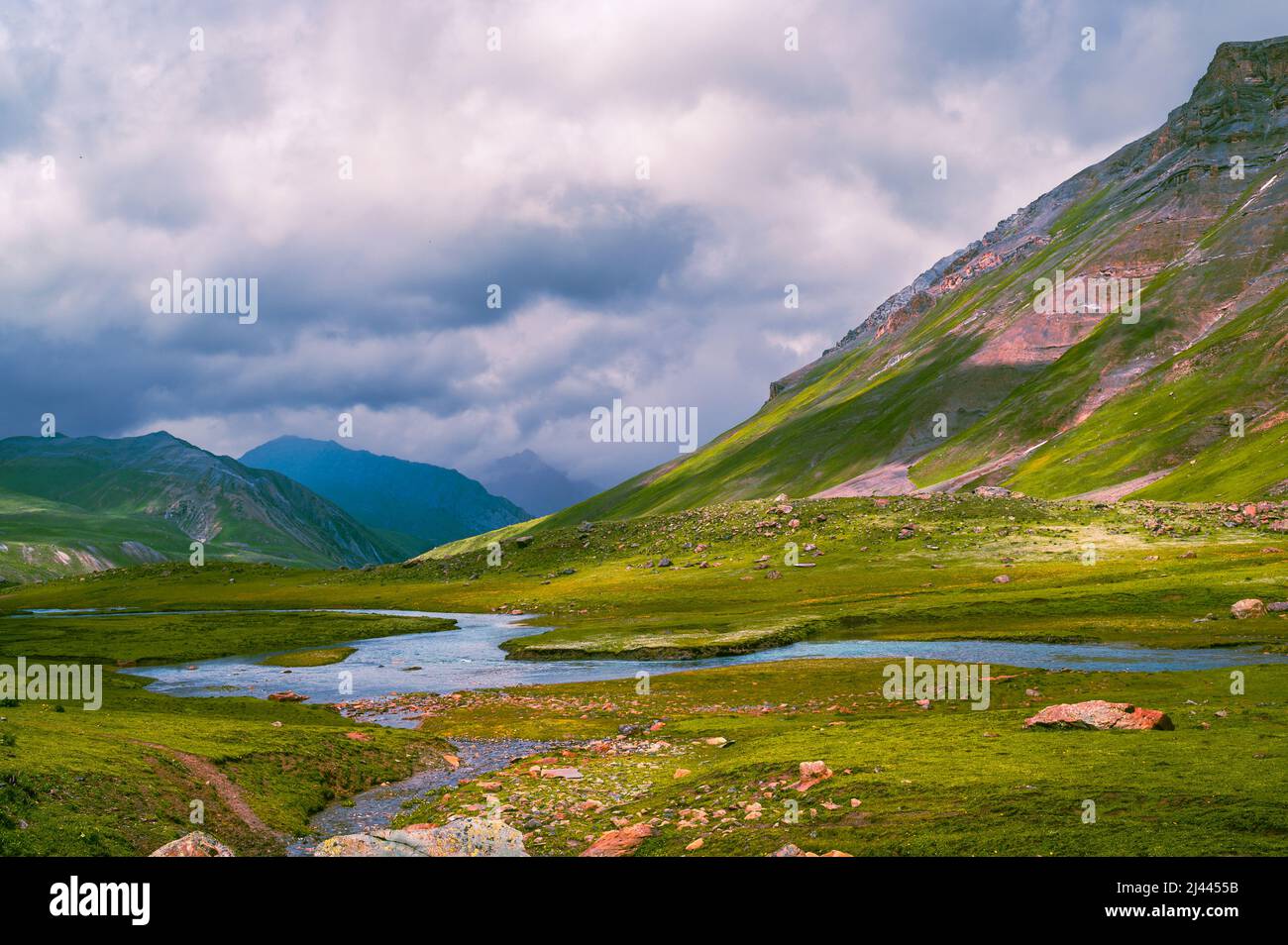 Landscape with mountains, clouds and blue sky. Beautiful meadows on the way from Kashmir Great Lakes Trek, Jammu and Kashmir, India. Stock Photo