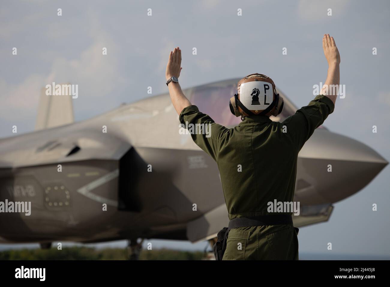 U.S. Marine Corps Sgt. Zachary Powell, a fixed-wing aircraft mechanic assigned to Marine Fighter Attack Squadron 121 (VMFA-121) guides an F-35B Lightning II aircraft during field carrier landing practices (FCLP) at Ie Shima Island, Okinawa, Japan, April 7, 2022. The FCLP trains the F-35B pilots for proficiency and mission readiness when deployed aboard aircraft carriers. (U.S. Marine Corps photo by Lance Cpl. Kyle Chan) Stock Photo