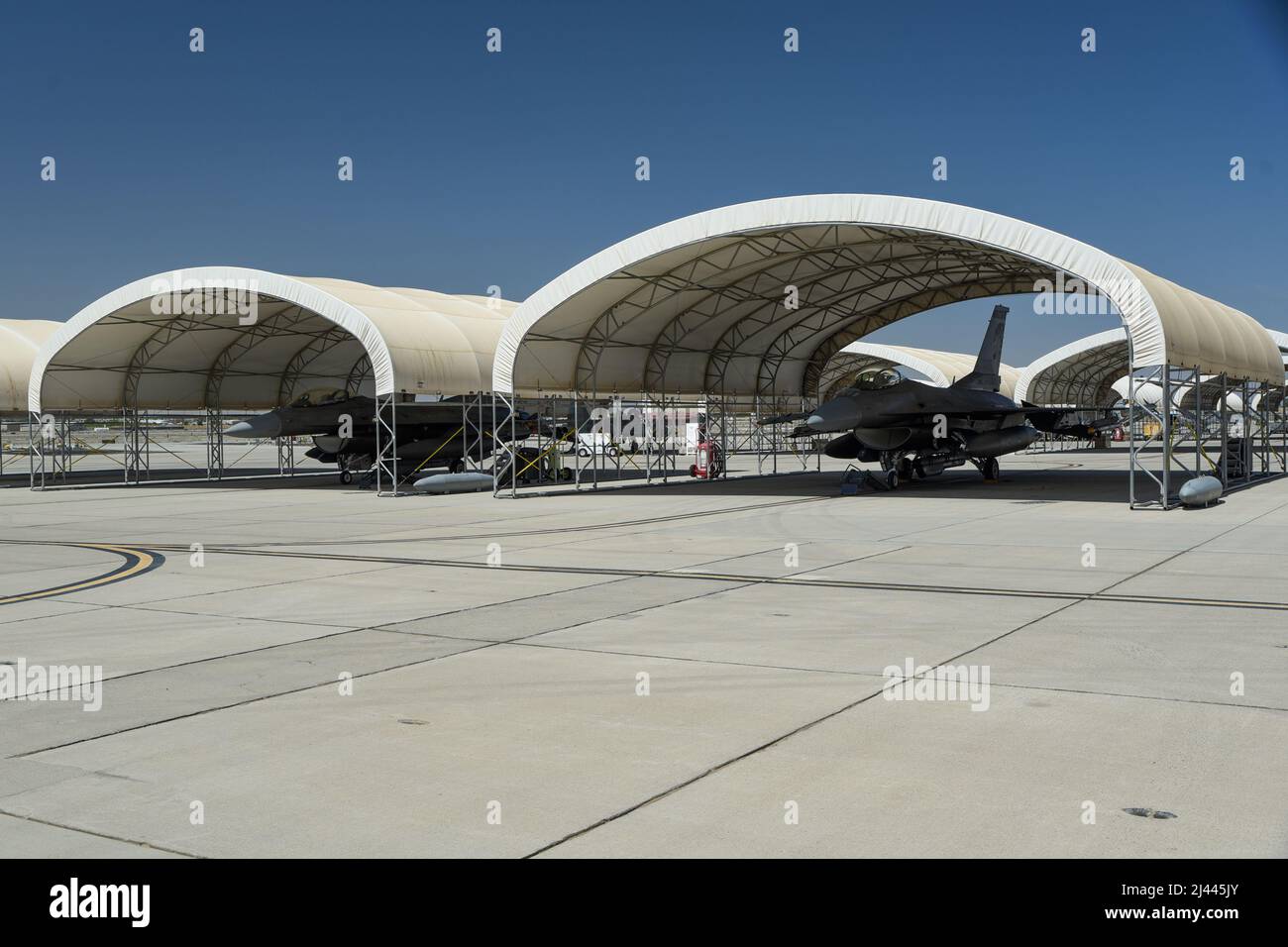 F-16 Fighting Falcons assigned to the 114th Fighter Wing park under a sun shade during Weapons and Tactics Instructor (WTI) course 2-22 at Marine Corps Air Station Yuma, Ariz., April 4, 2022. WTI is a seven-week training event hosted by Marine Aviation Weapons and Tactics Squadron One (MAWTS-1), providing standardized advanced tactical training and certification of unit instructor qualifications to support Marine aviation training and readiness, and assists in developing and employing aviation weapons and tactics. (U.S. Air National Guard photo by Tech. Sgt. Jordan M. Hohenstein) Stock Photo