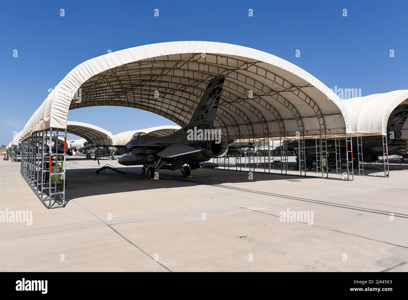 F-16 Fighting Falcons assigned to the 114th Fighter Wing park under a sun shade during Weapons and Tactics Instructor (WTI) course 2-22 at Marine Corps Air Station Yuma, Ariz., April 4, 2022. WTI is a seven-week training event hosted by Marine Aviation Weapons and Tactics Squadron One (MAWTS-1), providing standardized advanced tactical training and certification of unit instructor qualifications to support Marine aviation training and readiness, and assists in developing and employing aviation weapons and tactics. (U.S. Air National Guard photo by Tech. Sgt. Jordan M. Hohenstein) Stock Photo