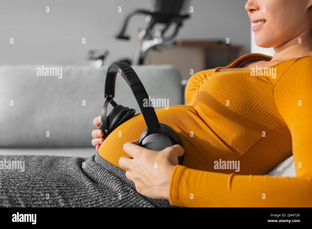 Pregnancy music. Pregnant woman holding headphones to foetus in womb