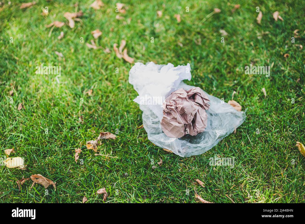 plastic bags and litter abandoned on green lawn, concept of respecting