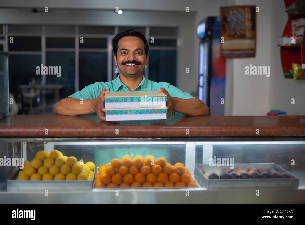 Sweet shop owner selling sweet to customer Stock Photo