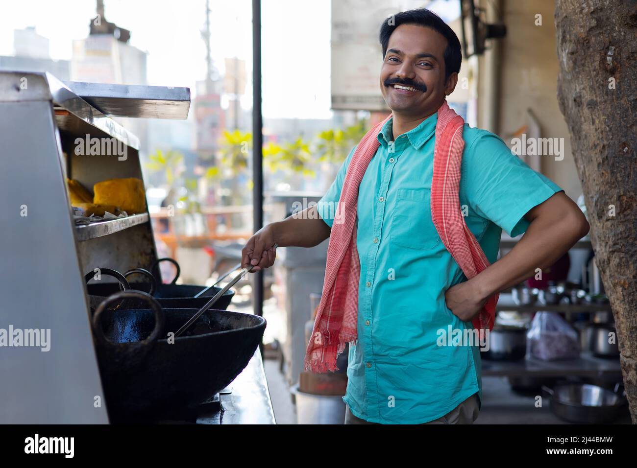 Street food vendor looking at camera with smile while making food at a stall Stock Photo